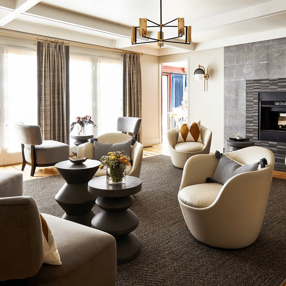 A stylish living room featuring modern chairs, decorative tables, and a cozy fireplace.