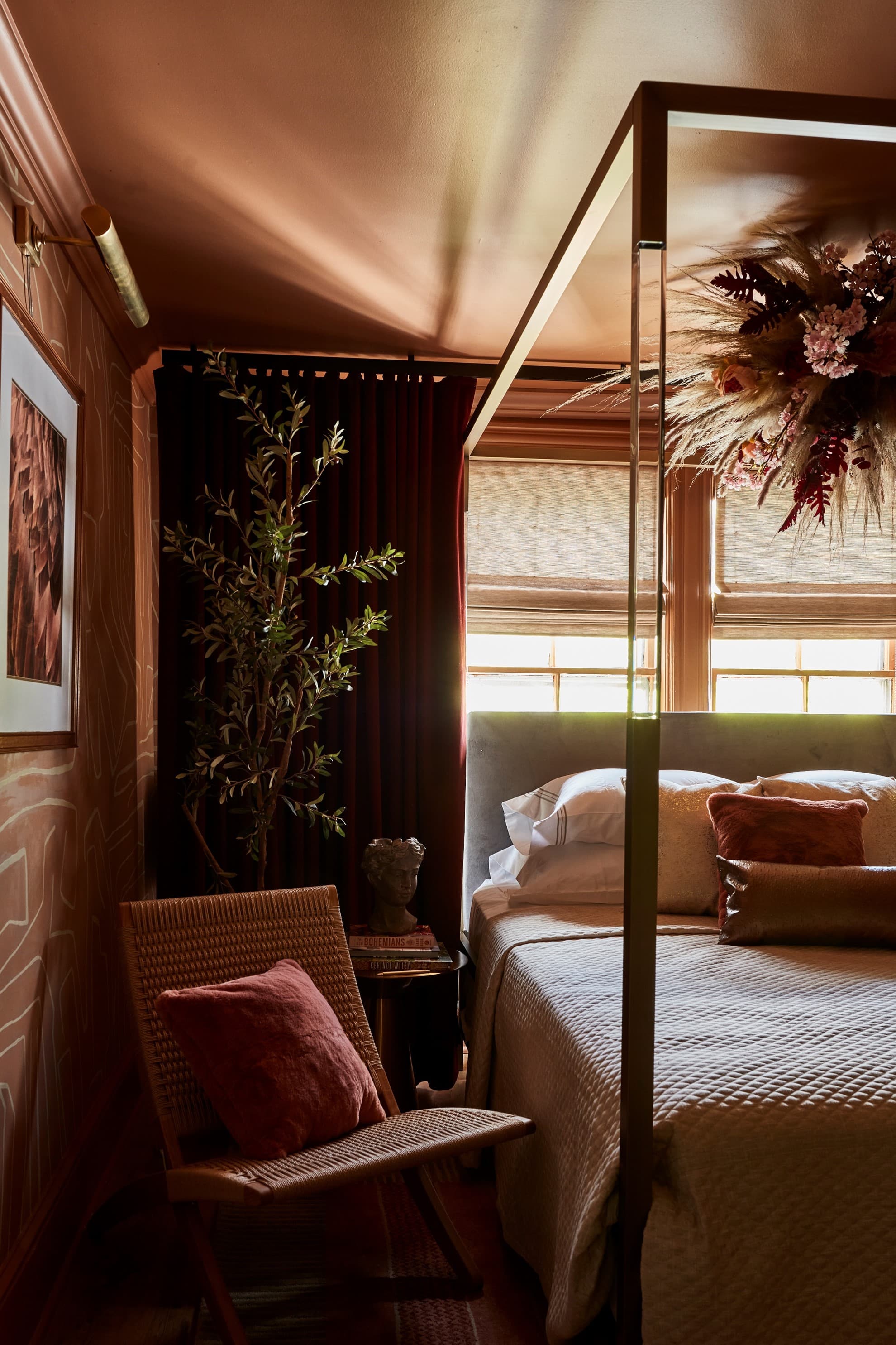 seating chair to the side of the bed with a plant behind and a side table