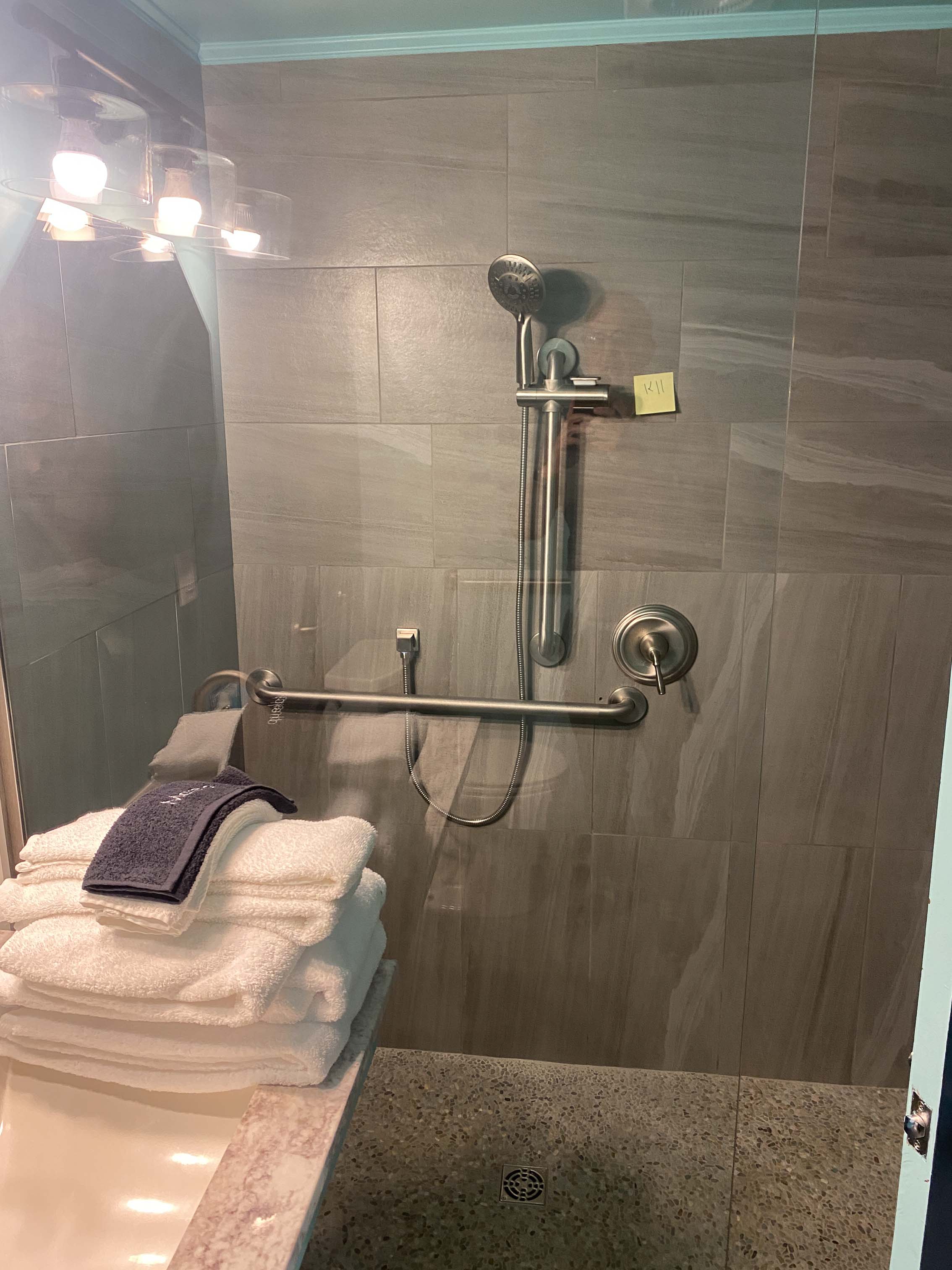 roll-in shower with gray slate tilework and grab bars on the walls