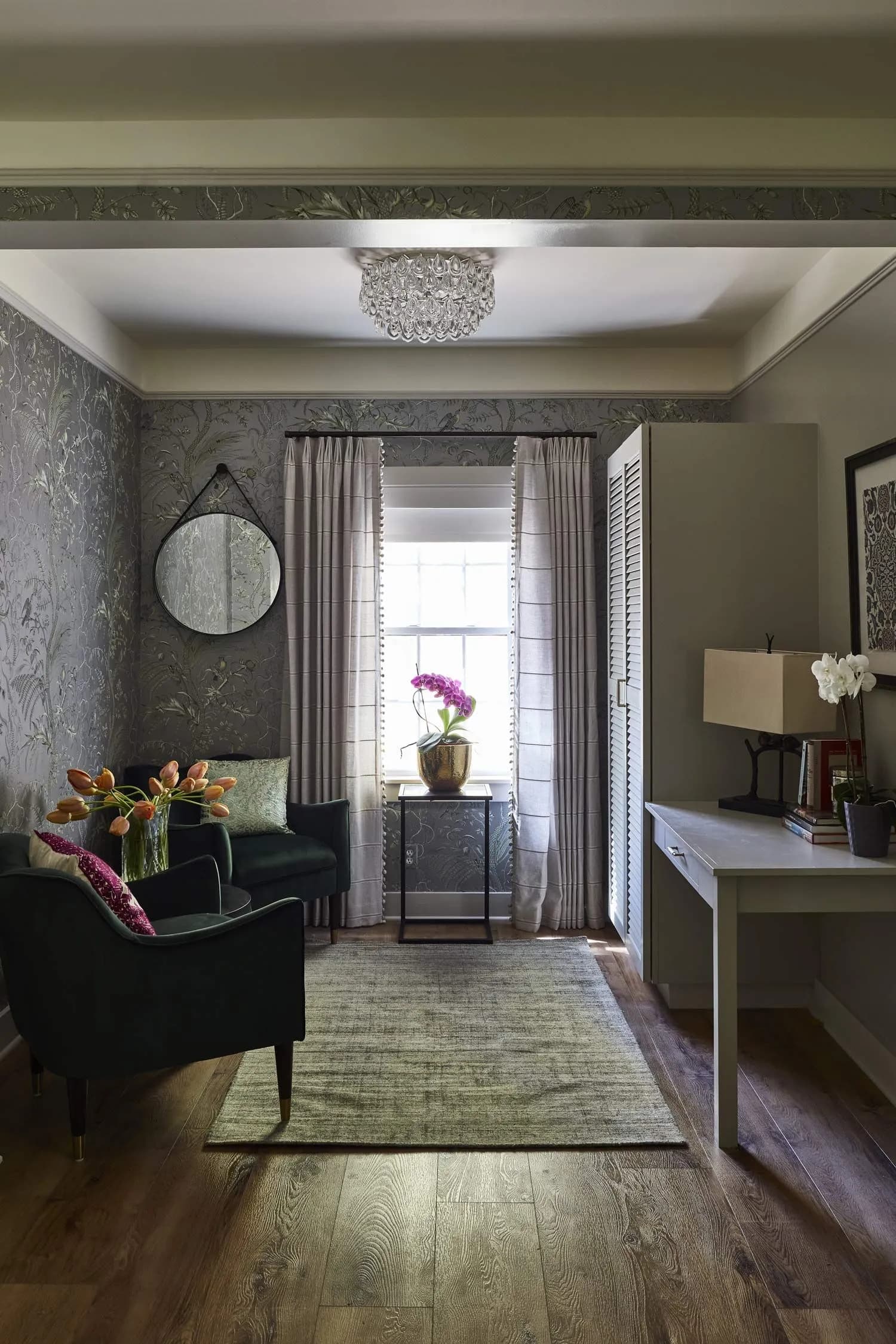 Sitting room with floral wallpaper, two armchairs, and a desk.
