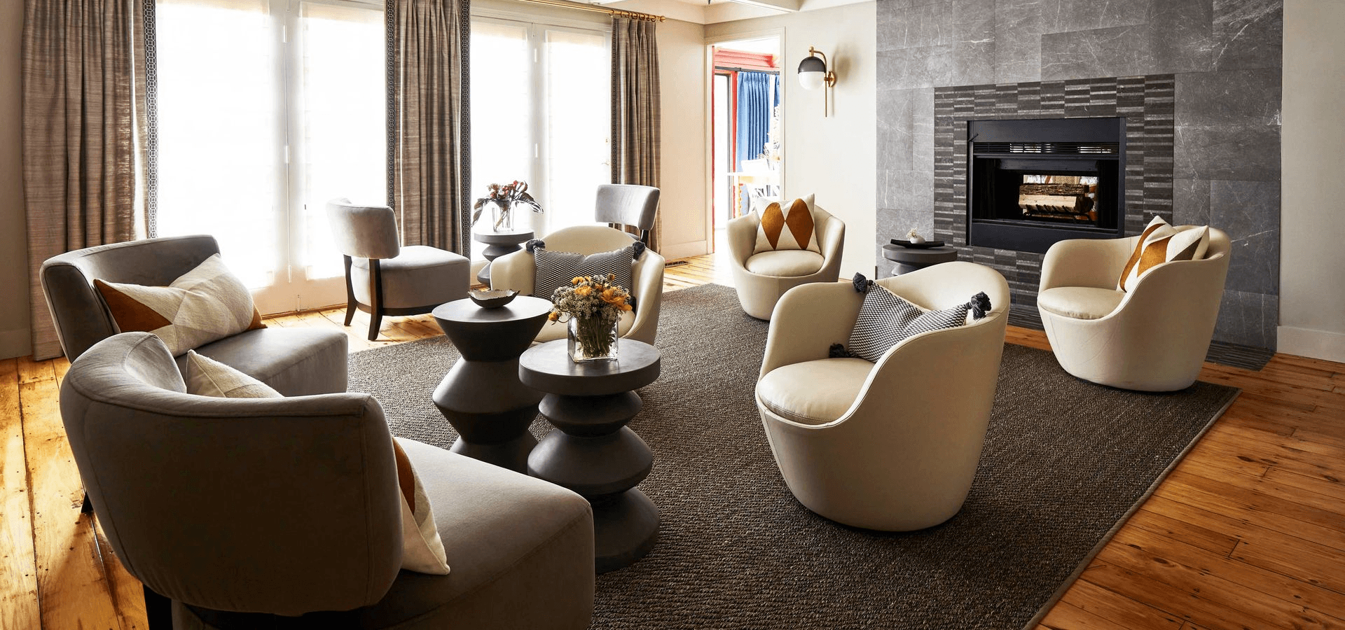 A modern living room featuring stylish furniture, a cozy fireplace, and large windows allowing natural light.